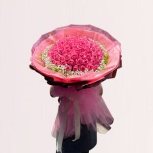 Indulge in the luxury of this grand bouquet of pink roses carefully arranged in a cascading bouquet wrapped in soft pink tulle. Complemented by delicate white blooms and lush greenery, this magnificent bouquet is perfect for expressing love and affection on special occasions