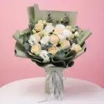Bouquet of peach roses and white eustoma with eucalyptus wrapped in olive green paper.
