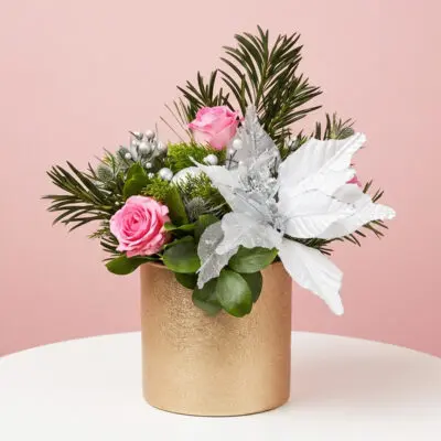 Pink roses and silver poinsettia Christmas vase arrangement with festive greens and silver ornaments.
