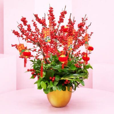 Red Berry Prosperity Pot with Red berry branches and lush greens in a gold pot arrangement, with Chinese New Year lantern charms and auspicious tags