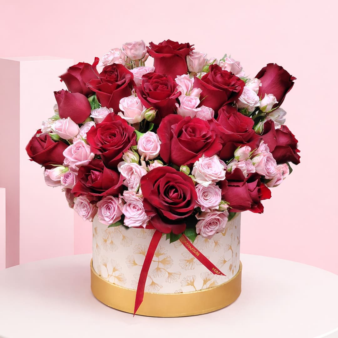 01 Rose Duo Box Deep with red roses and soft pink spray roses in a premium white-and-gold hatbox arrangement, finished with a satin ribbon.