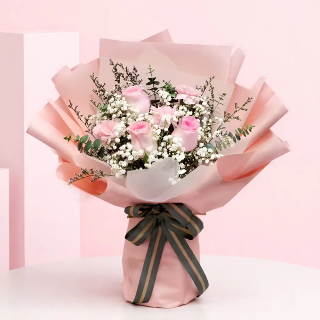 Cupid Blush Peach Wrap Bouquet with Blush pink roses and baby’s breath in a peach wrap, finished with a black ribbon.