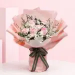 Cupid Blush Peach Wrap Bouquet with Blush pink roses and baby’s breath in a peach wrap, finished with a black ribbon.