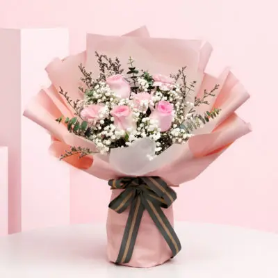 Cupid Blush Peach Wrap Bouquet with Blush pink roses and baby’s breath in a peach wrap, finished with a black ribbon.