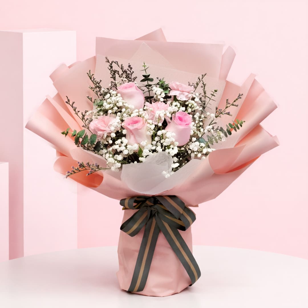 01 Cupid Blush Peach Wrap Bouquet with Blush pink roses and baby’s breath in a peach wrap, finished with a black ribbon.