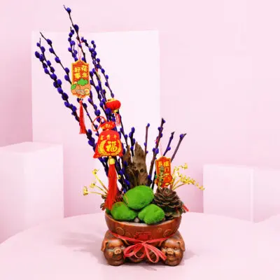 Fortune CNY Moss Bowl Centerpiece with lucky stems, green moss, and botanical accents finished with red Chinese New Year charms and prosperity tags.