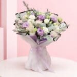 Handheld pastel flower bouquet with lavender whisper, white, and blush blooms wrapped in elegant paper with ribbon.