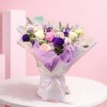 Pastel glow bouquet with lavender, pink and white blooms wrapped in holographic shimmer paper with ribbon.
