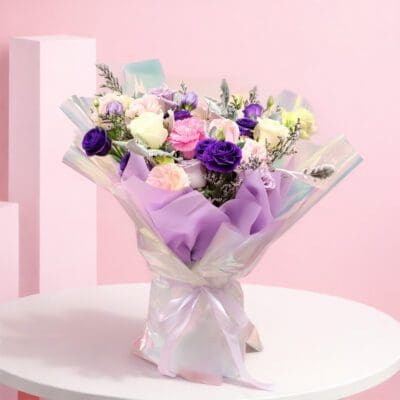 Pastel glow bouquet with lavender, pink and white blooms wrapped in holographic shimmer paper with ribbon.
