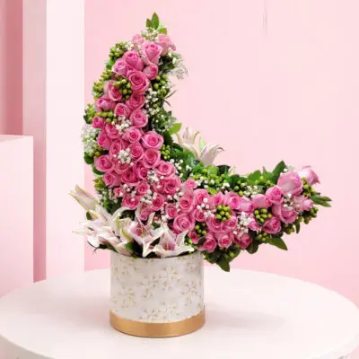 crescent bloom luxe consists of Pink roses are arranged in a crescent/curved design along with calla lilies and fillers in a decorative box