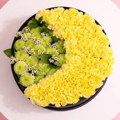 Yellow Carnation & Green Ping Pong Box Black, delicate wax flowers, styled with lush greenery for a vibrant and cheerful look