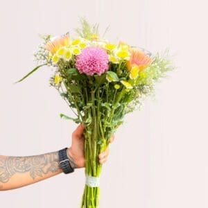Person presenting a vibrant floral arrangement.