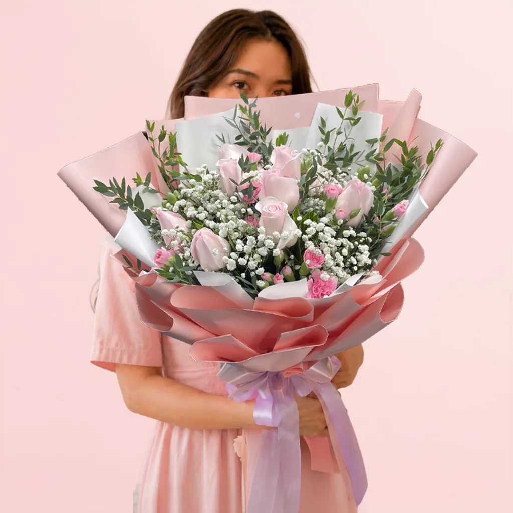 Blushing Beauty Bouquet featuring soft pink roses, bright pink accent blooms, baby's breath, and fresh greenery wrapped in elegant pink and white paper.