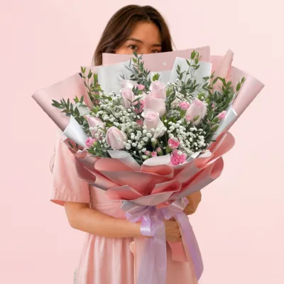 Blushing Beauty Bouquet featuring soft pink roses, bright pink accent blooms, baby's breath, and fresh greenery wrapped in elegant pink and white paper.