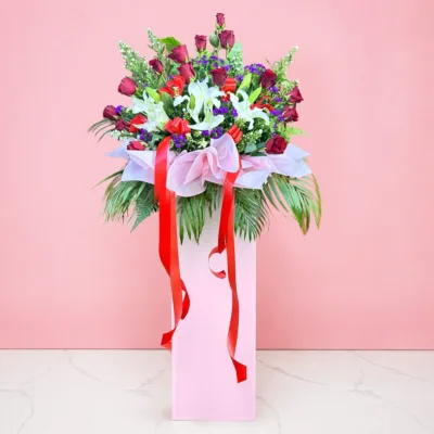Grand Opening flower stand with red roses, white lilies, purple fillers and red ribbons.