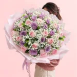 50 pink and lilac roses bouquet with baby’s breath wrapped in pastel pink paper