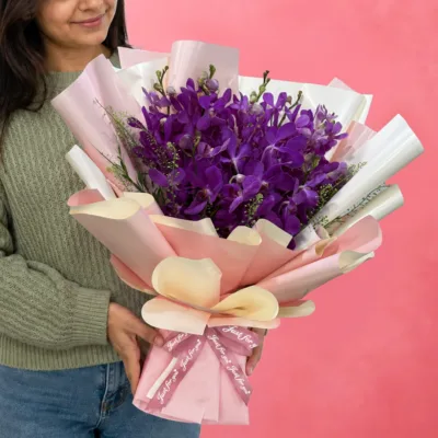 15 purple Mokara orchids arranged in a stylish peach wrap.