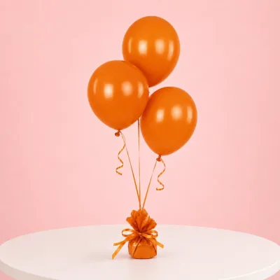 Orange party balloons arranged as a trio on a white table
